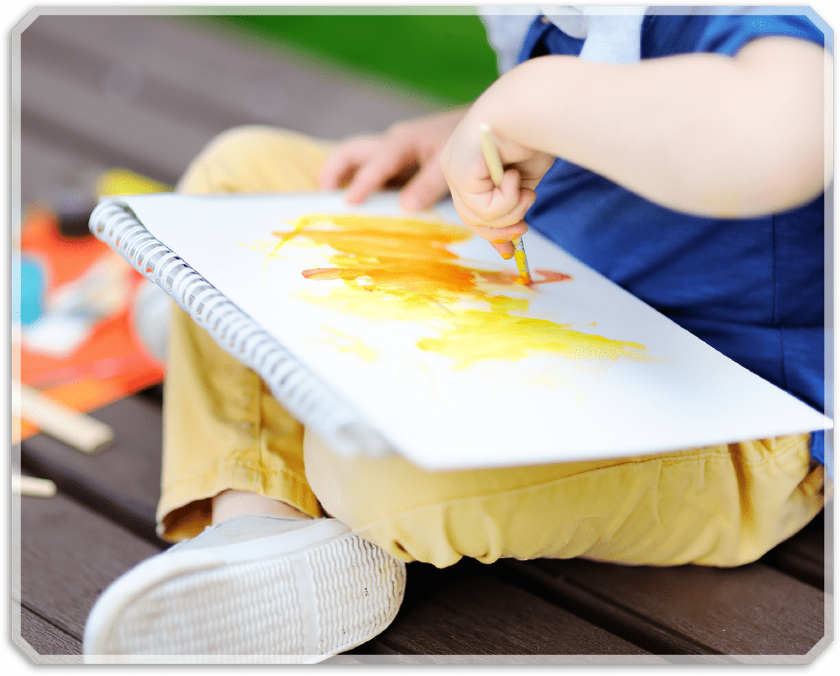 A child sitting with crossed legs and painting on a piece of paper