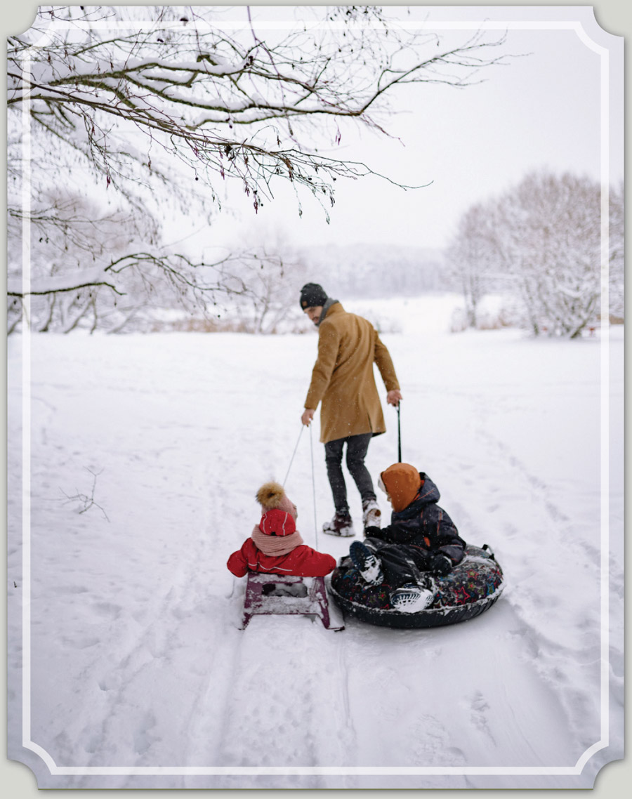 man pulling his children on sleds in the snow
