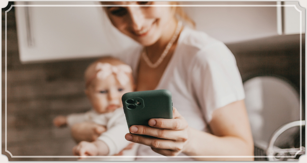 Mother holding baby and iphone with green case
