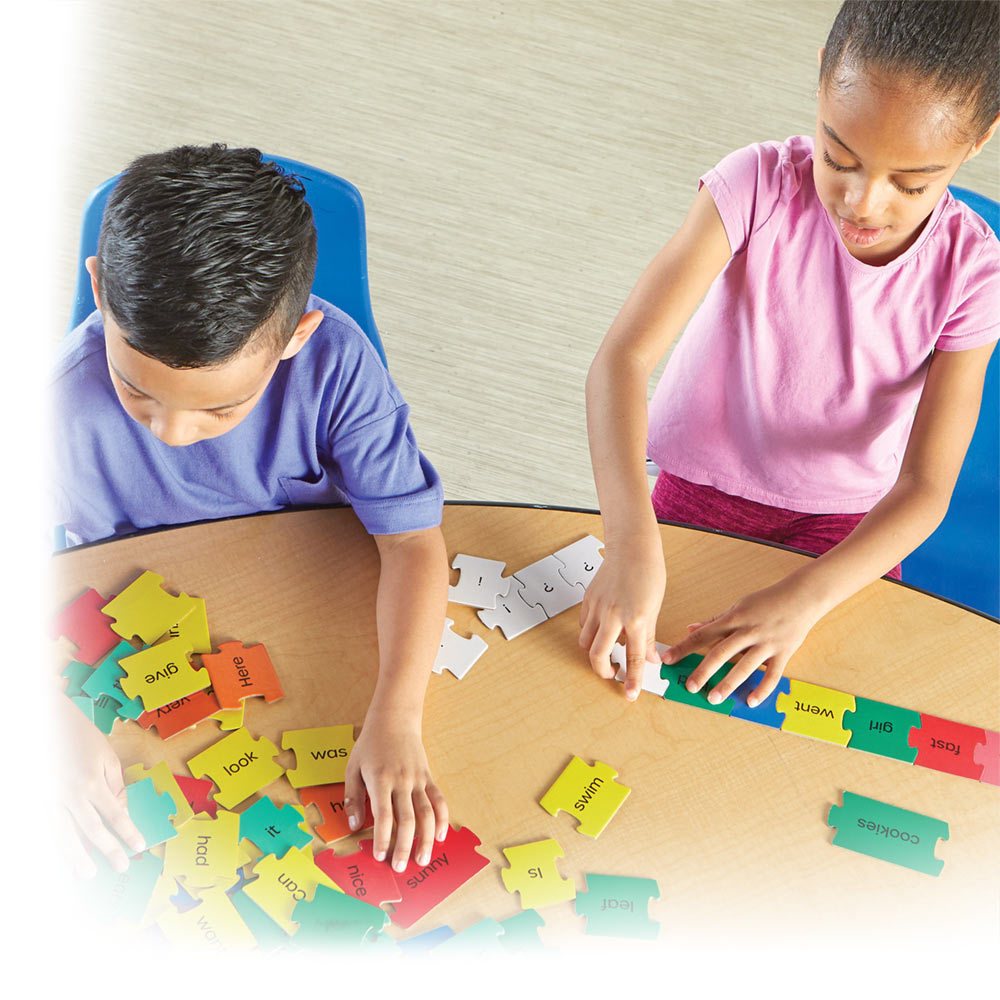 Two young kids at a table doing sentence puzzles