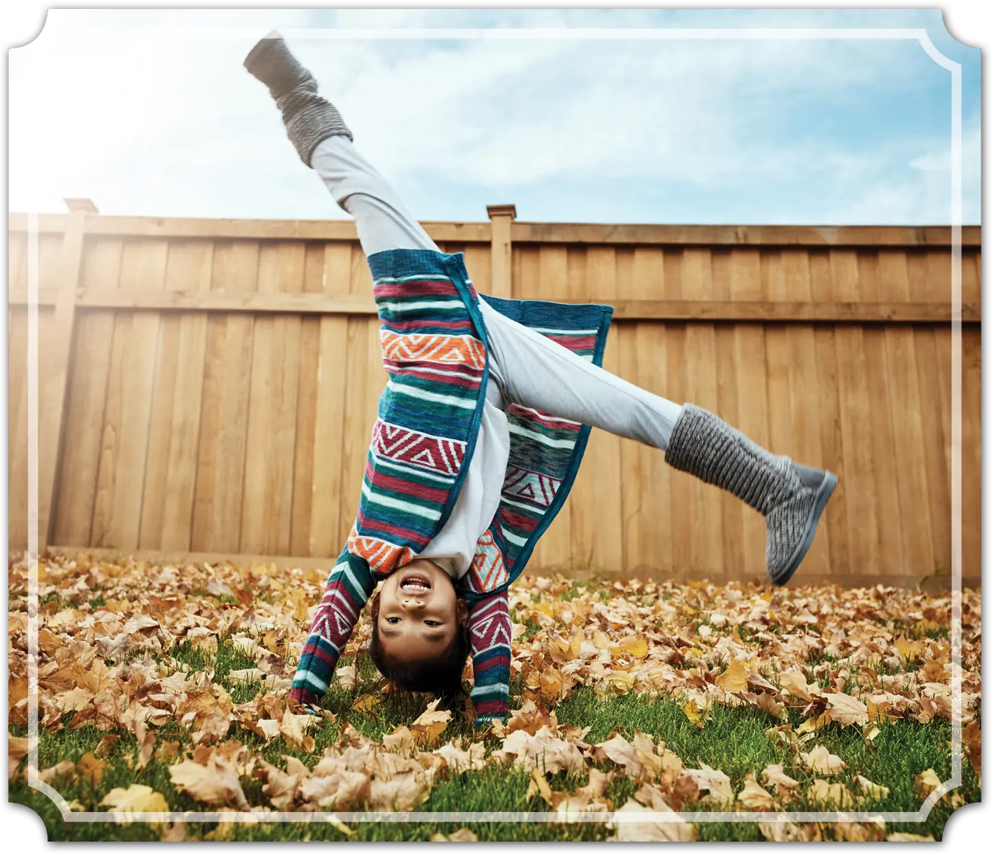 little girl doing a cartwheel in the backyard with leaves on the grass