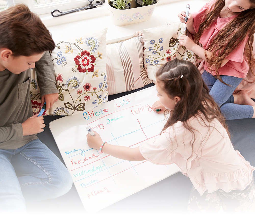 3 siblings making a chore list on a small whiteboard