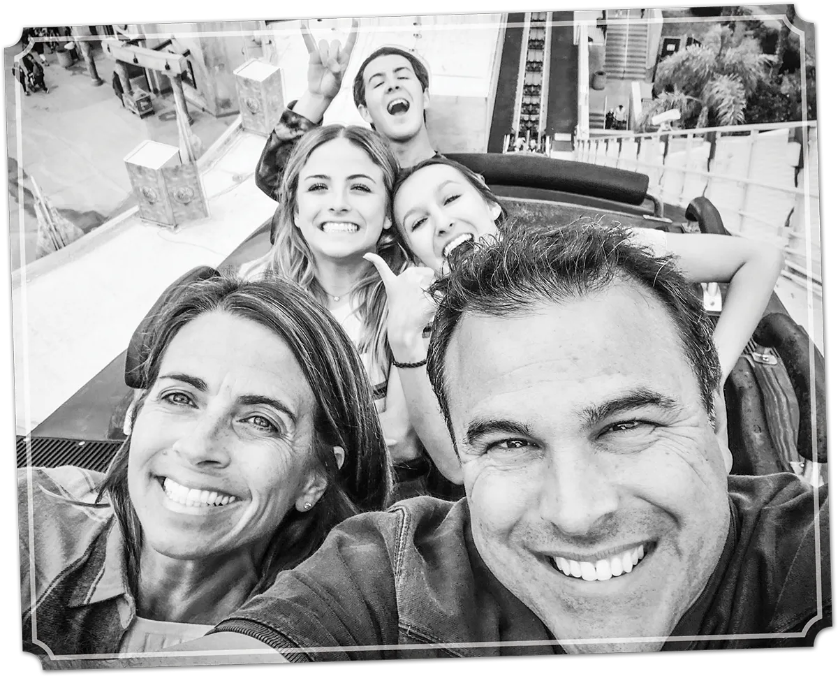 family taking selfie going up a roller coaster