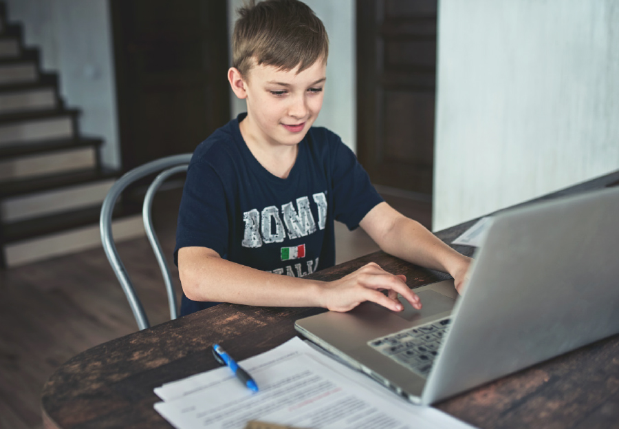 young boy on laptop at wooden table