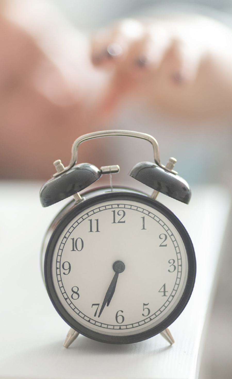 blurred hand reaching out behind a clock