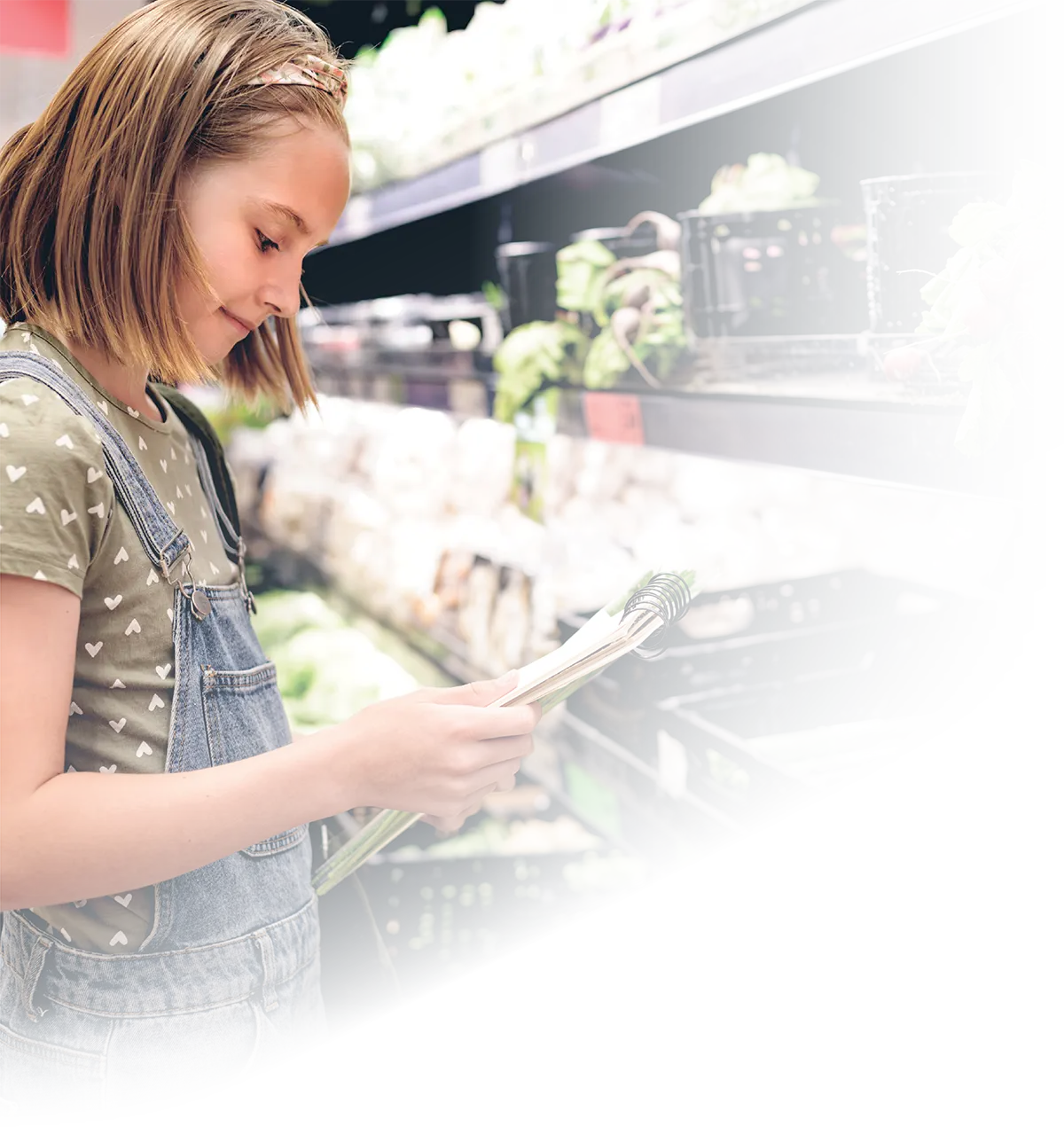 Young person in a grocery store holding a notebook.