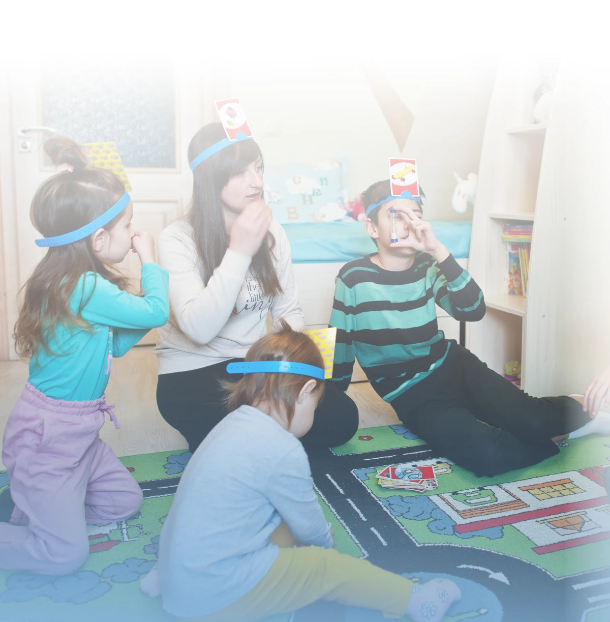 kids sitting on the floor and playing the game Hedbanz