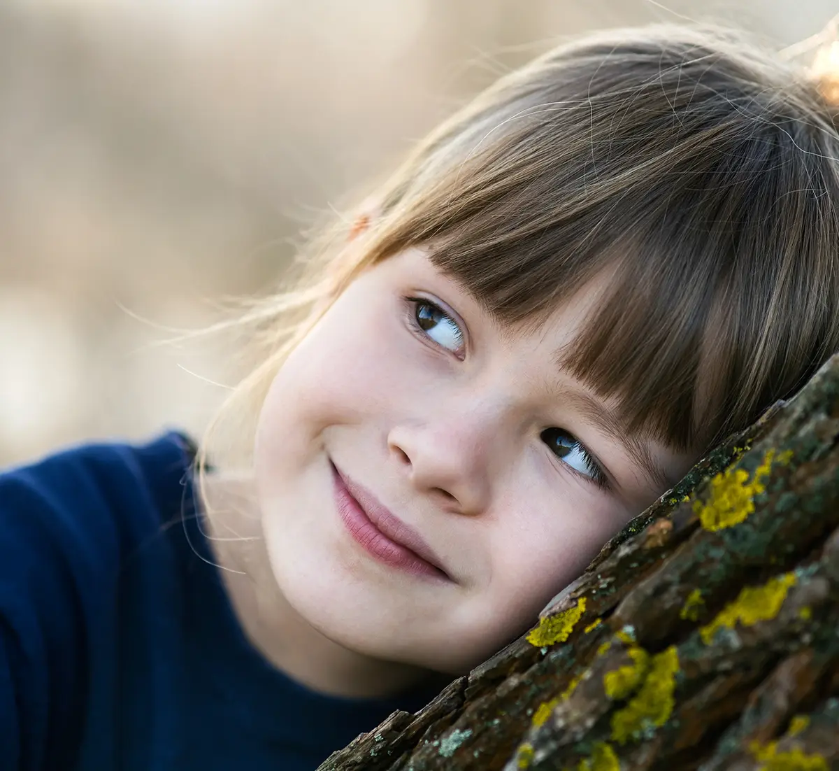 closeup of a kid lying against a tree