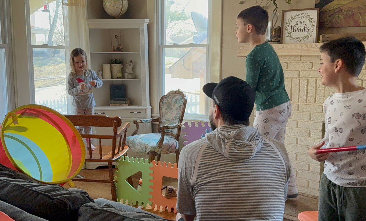 family smiling and interacting in a living room setting with toys