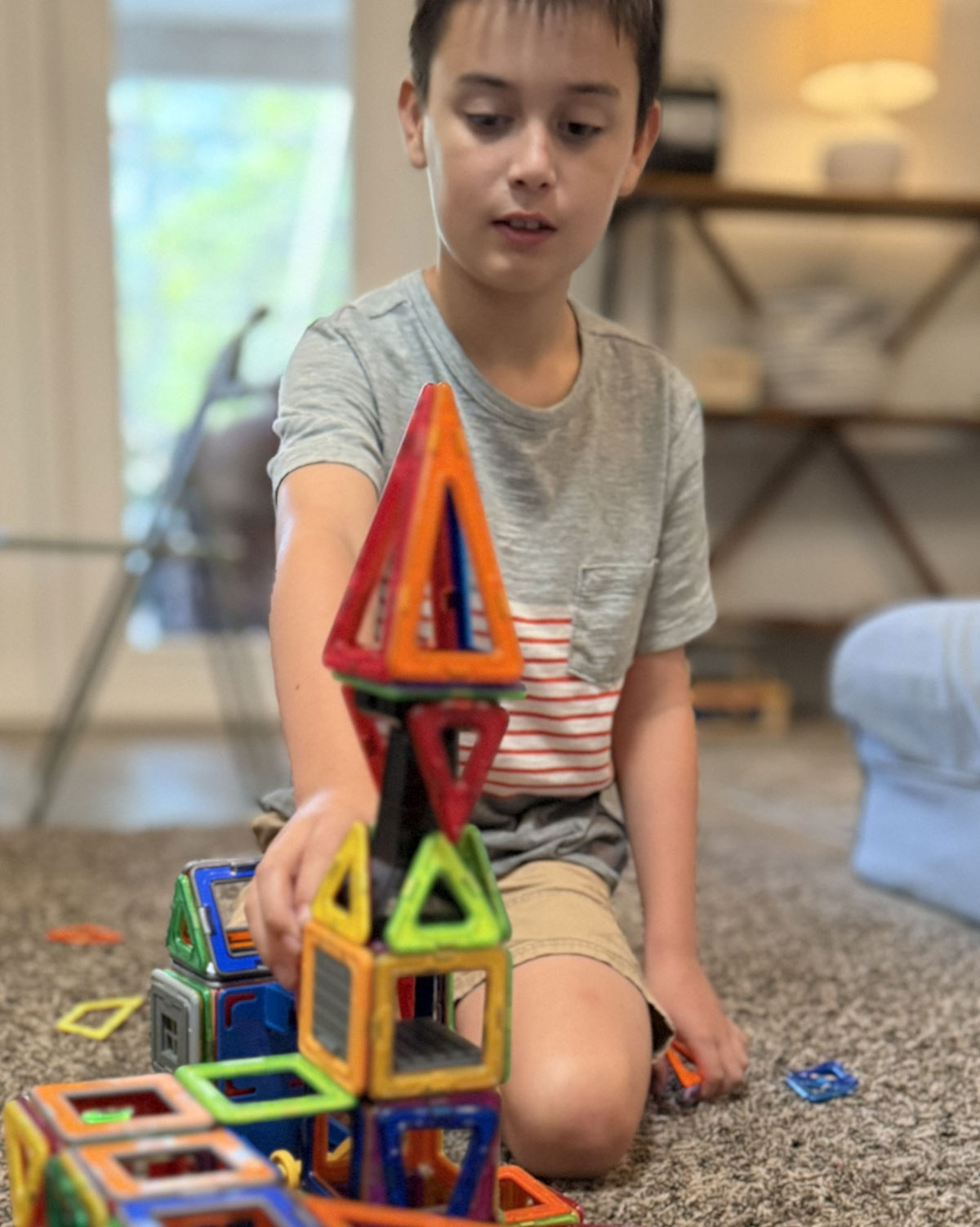 boy building tower out of magnetic shapes