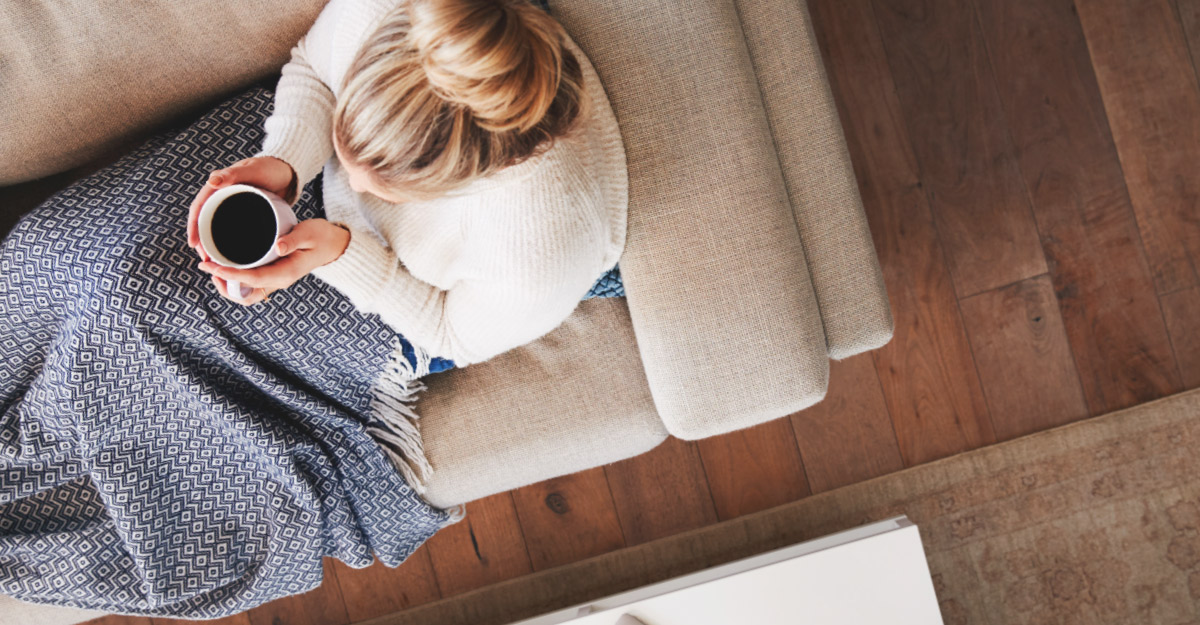 woman holding coffee while sitting on couch
