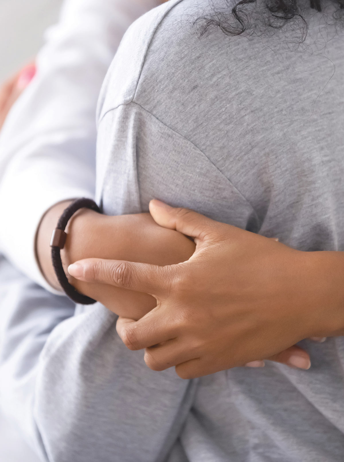 A close-up image showing one person offering comfort by placing a supportive hand on another person's arm.